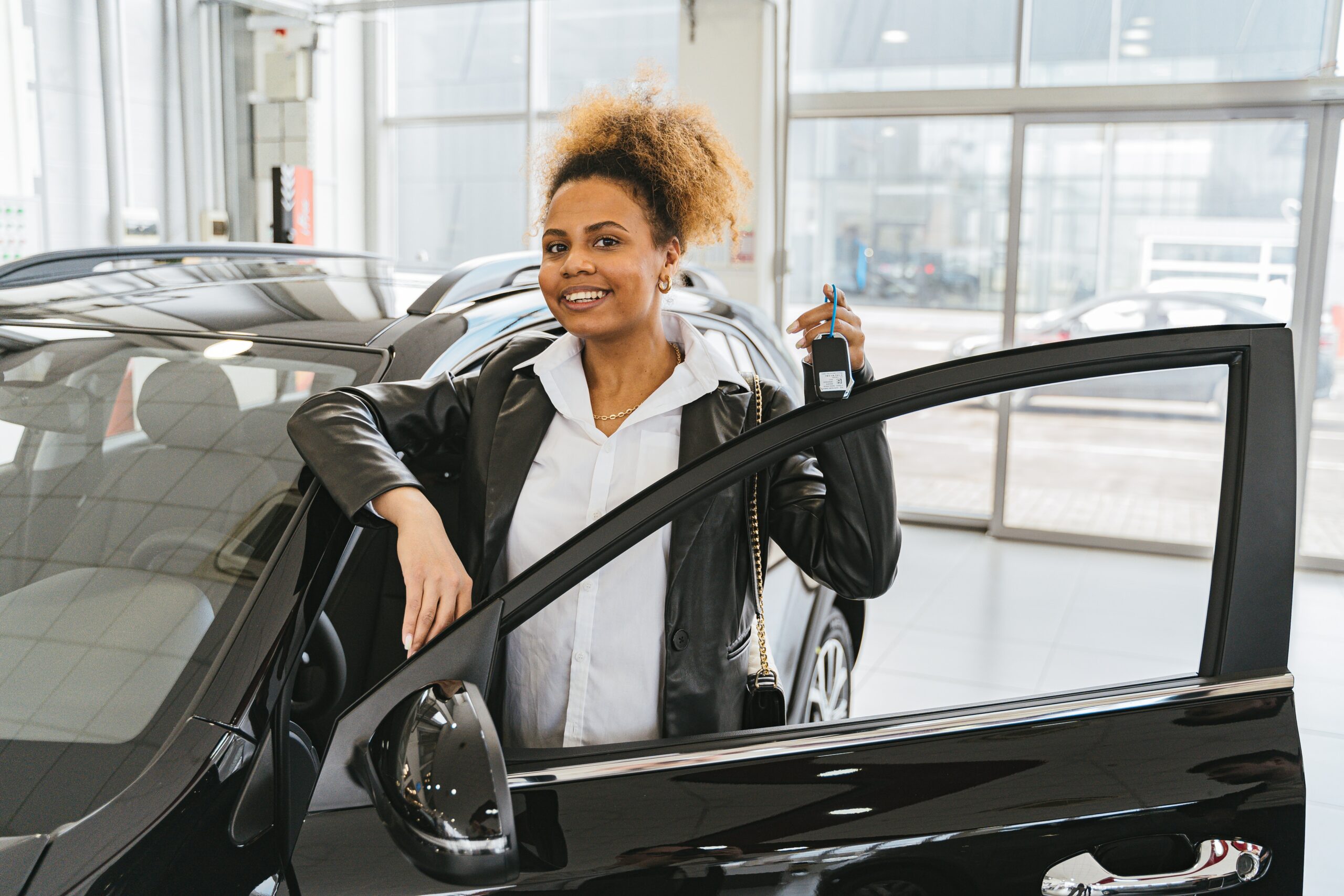 Woman holding keys with new car