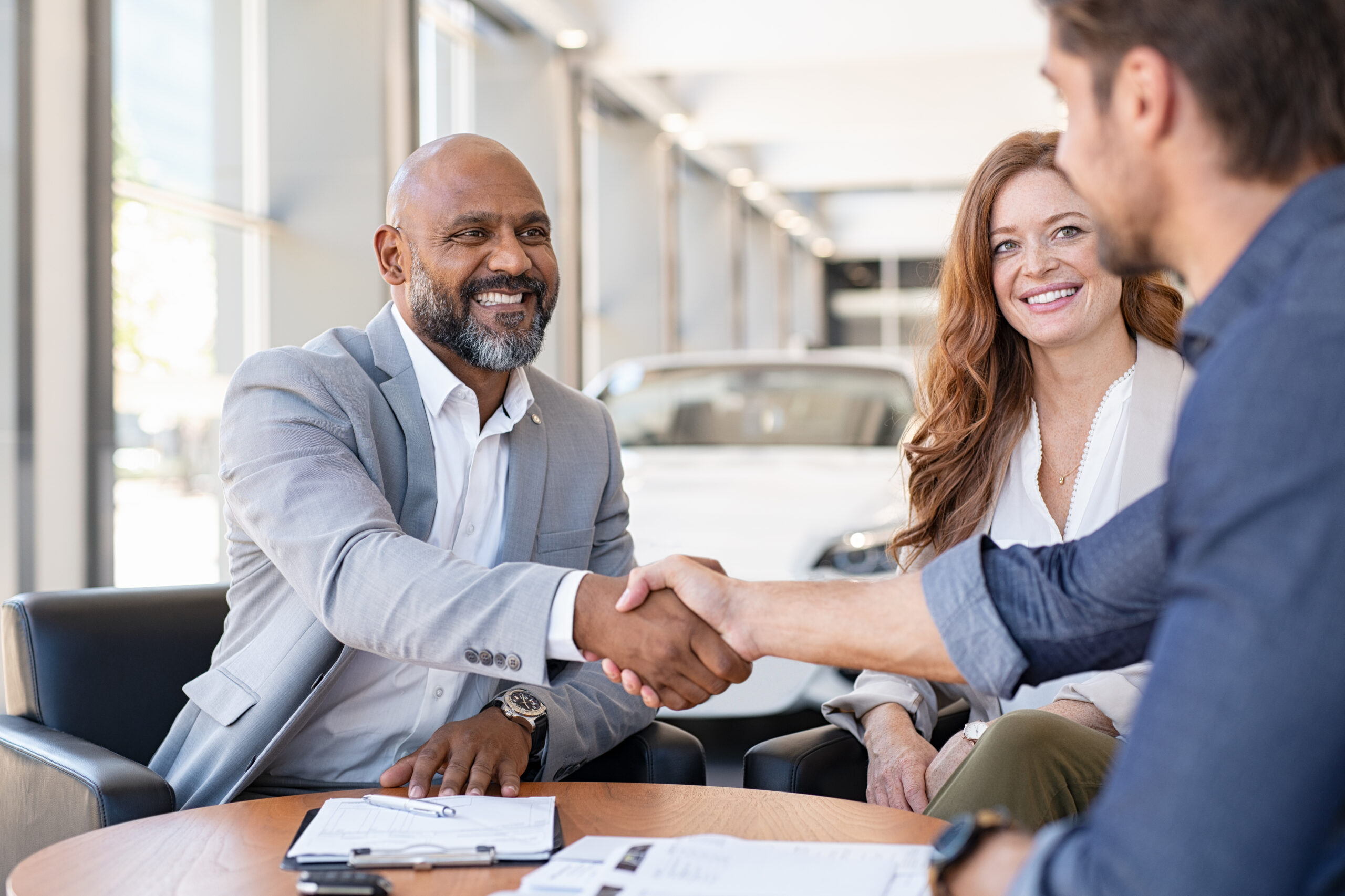 couple buying new car shaking hands