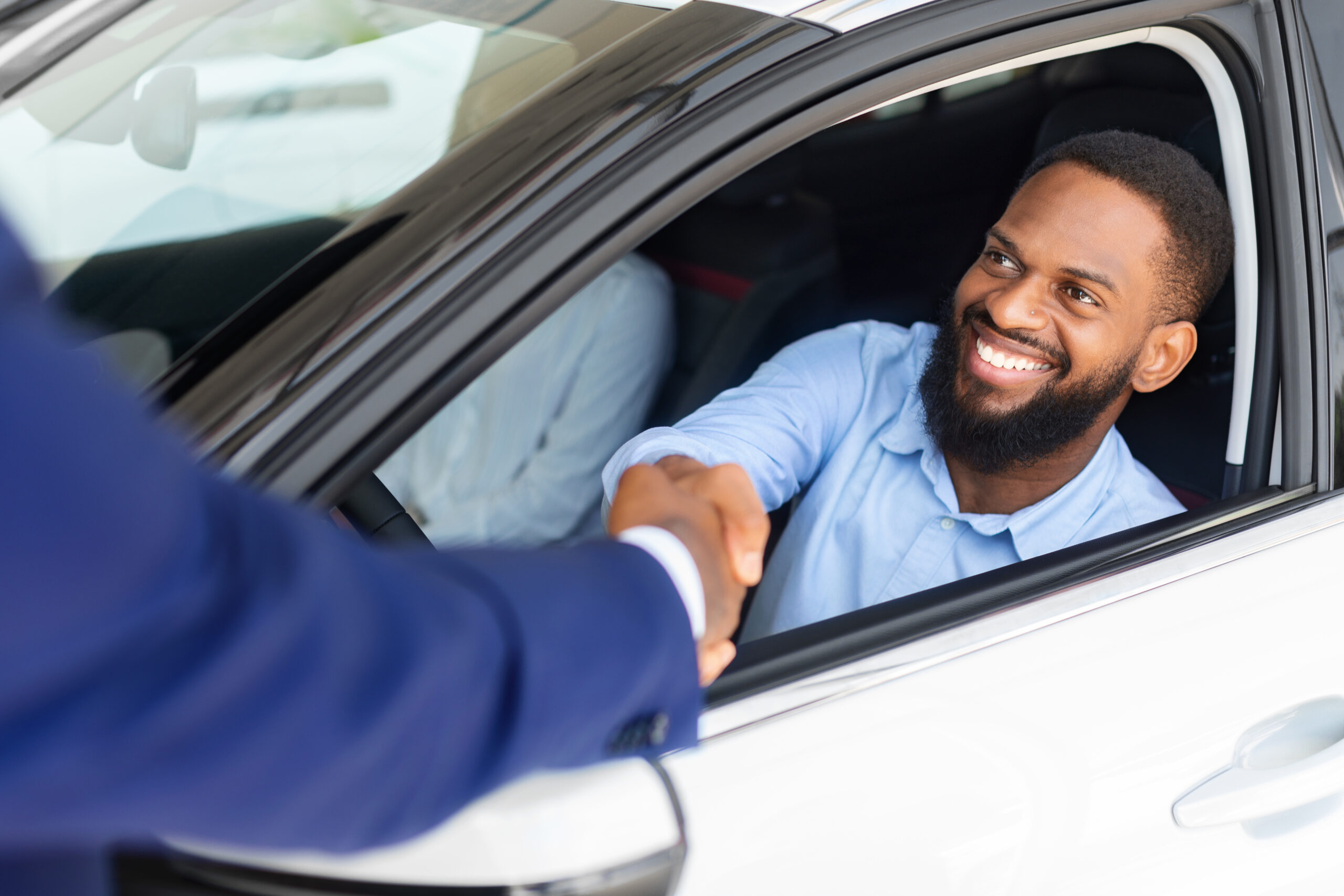 Man shaking someones hand out car window