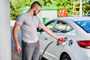 Young man refueling car tank with gasoline.